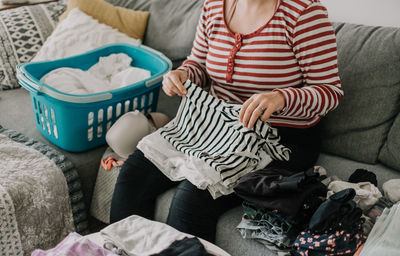 Close-up photo of woman folding laundry on sofa