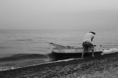 Rear view of man on beach against sky