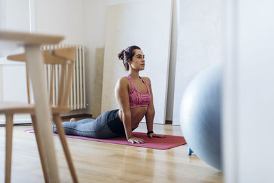 Focused ethnic woman practicing yoga at home