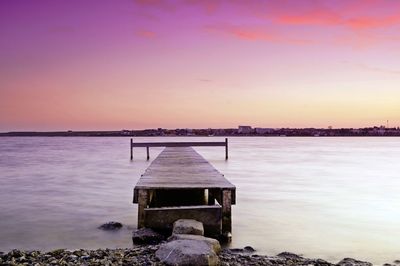 Built structure on rocks by sea against sky during sunset