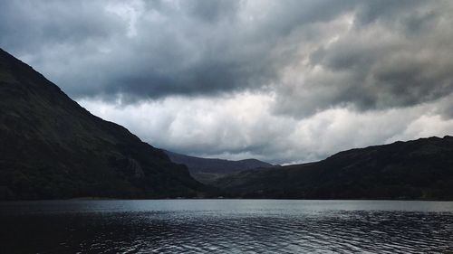 Scenic view of lake and mountains against cloudy sky