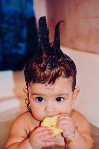 Close-up of cute baby girl playing with rubber duck while bathing in bathtub