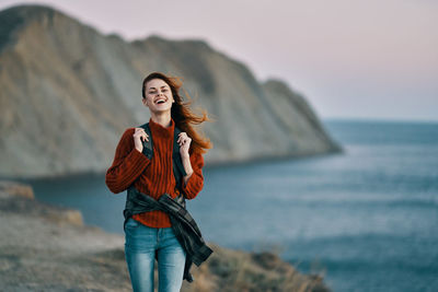 Full length of young woman at beach against sky