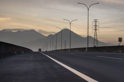 Empty road against sky during sunset