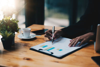 Midsection of businesswoman writing on document