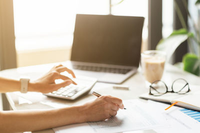 Midsection of woman using laptop on table