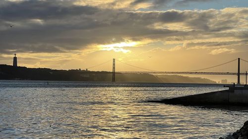 View of suspension bridge over river at sunset