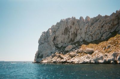 Rock formation in sea against clear sky