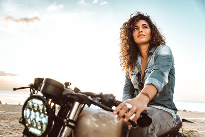 Portrait of smiling woman riding motorcycle against sky