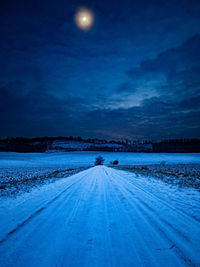 Snow covered road against sky at night