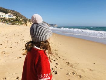 Winter at the beach with girl in bobble hat and christmas jumper 