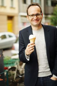 Portrait of man holding ice cream standing street