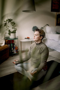 Lesbian woman with eyes closed practicing yoga at home