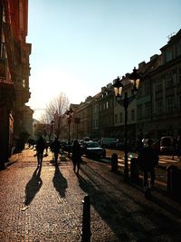 People on street against clear sky at sunset