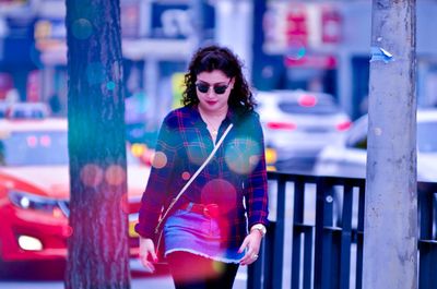 Young woman wearing sunglasses walking on footpath 