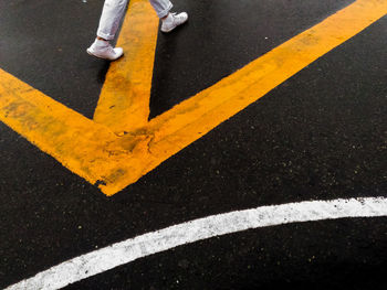 Low section of person walking on arrow symbol over road