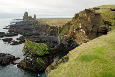 Scenic view of rocks by sea against sky