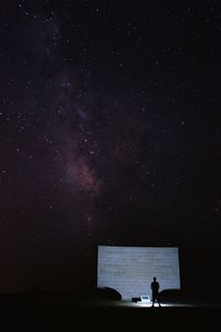 Rear view of man standing against star field at night