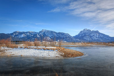 Scenic view of lake by snowcapped mountains against sky