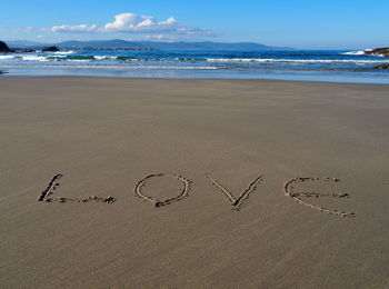 Text on beach against sky