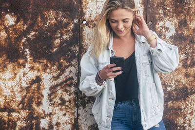 Young woman using mobile phone while standing at camera