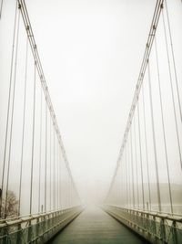 Footbridge against sky during foggy weather