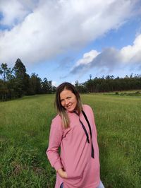 Portrait of smiling young woman standing on field