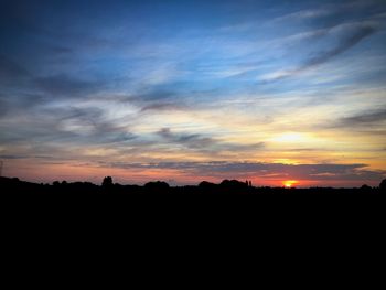 Silhouette landscape against dramatic sky during sunset