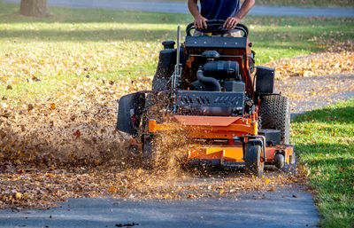 A worker rides on a large mulch-er that grinds up leaves into micro pieces and creates a lawn mulch