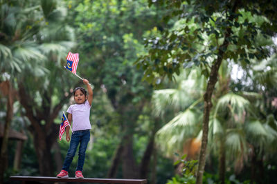 Boy standing on plant against trees