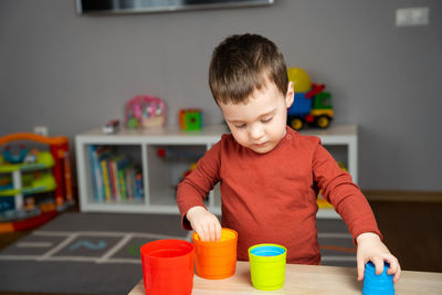 A cute little toddler boy of two years old sits at a children's table 