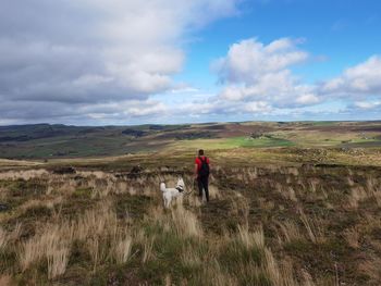 Rear view of dog on field against sky