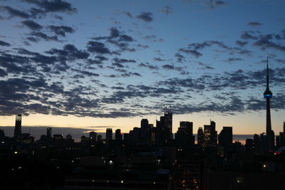 Illuminated buildings in city against sky at sunset