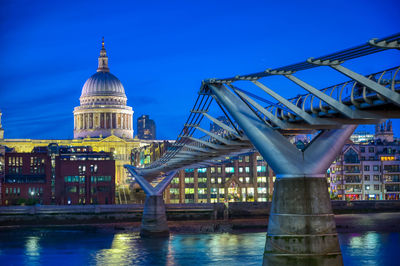 Bridge over river against blue sky in city