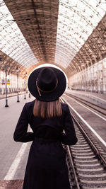 Rear view of woman standing at railroad station