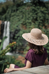 Rear view of woman wearing hat standing on table