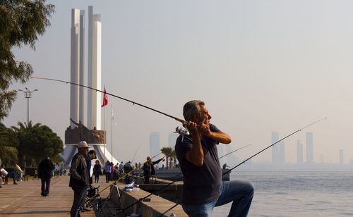 People on sea against clear sky