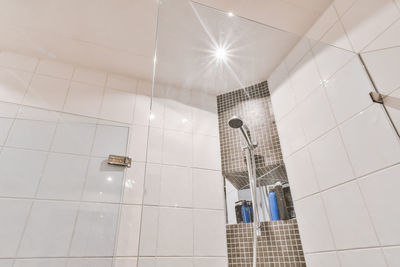 Low angle view of illuminated lighting equipment hanging on ceiling in bathroom