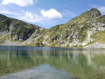 Scenic view of lake by mountains against sky