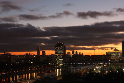 Illuminated buildings in city against sky at dusk