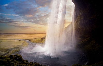 Scenic view of waterfall against sky during sunset