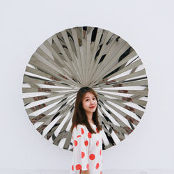 Portrait of beautiful young woman standing against wall