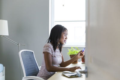 Woman working at home office seen through doorway