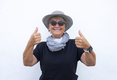 Portrait of smiling woman wearing hat standing against white background