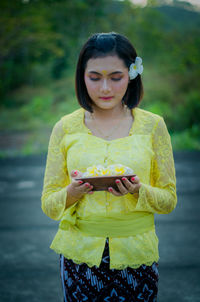 Young woman looking away while standing outdoors
