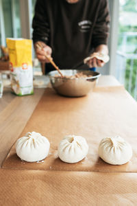 Midsection of a woman preparing bao on a table. it's a traditional chinese food. 