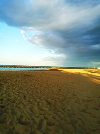 Scenic view of beach against cloudy sky