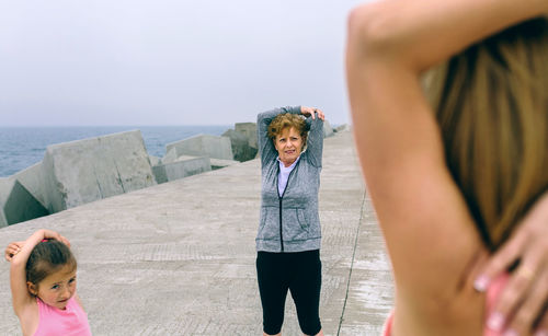 Girl with mother and grandmother exercising on pier