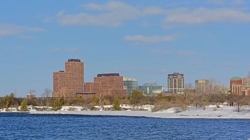 Sea by buildings against sky in city