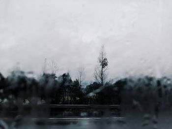 Water drops on glass window against sky